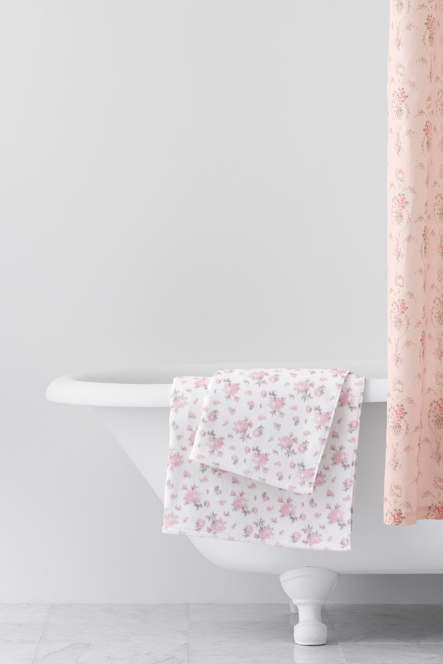 vintage-inspired delicate repeating mini floral print bath towel in a soft pink against a white back