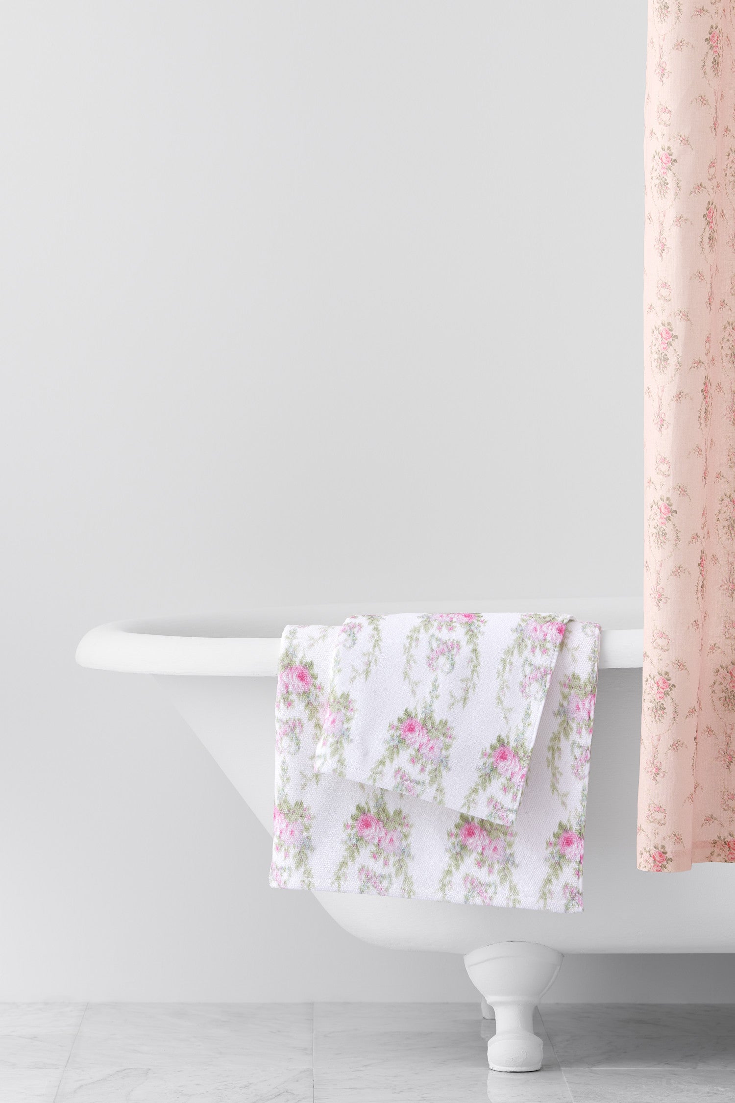 vintage-inspired repeating floral print bath towel in a soft pink against a white back