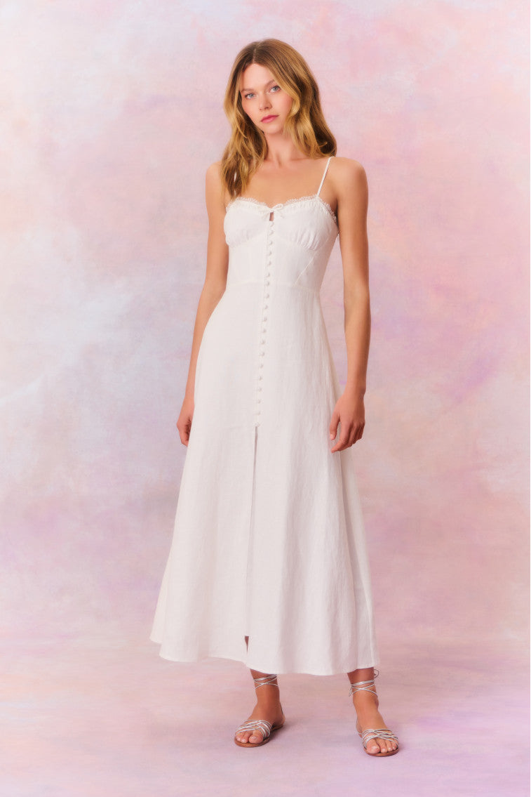 White maxi dress featuring thin spaghetti straps, bustier-inspired cups at the bust with shirring details, a playful keyhole cutout, a center front placket that stops at the hip above a center front slit. 