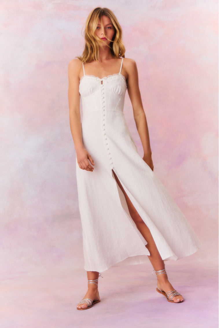 White maxi dress featuring thin spaghetti straps, bustier-inspired cups at the bust with shirring details, a playful keyhole cutout, a center front placket that stops at the hip above a center front slit.