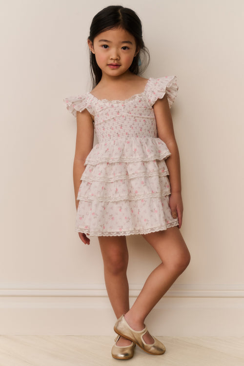 Young girl wearing a floral dress against a plain background