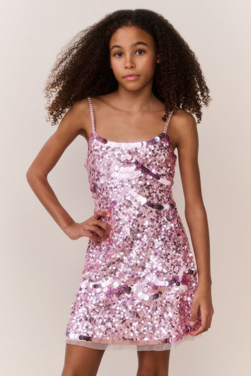 Young girl wearing a pink sequin dress against a plain background