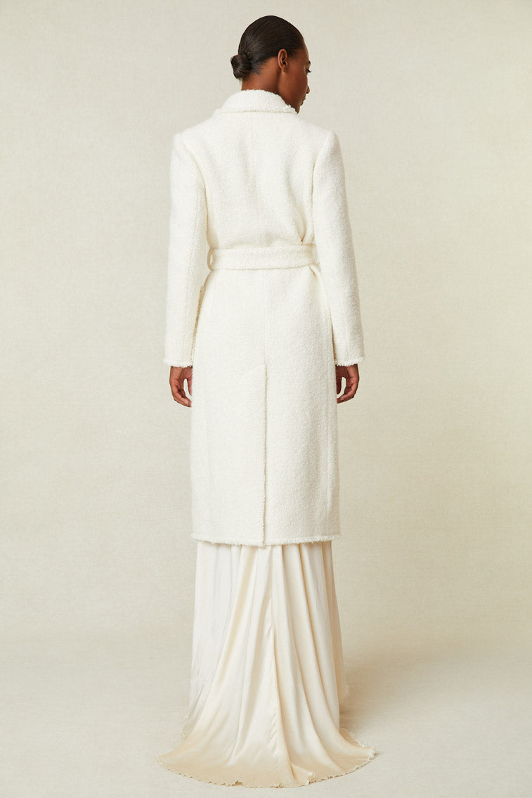 Back image of model wearing midi length coat with waist tie and pockets.