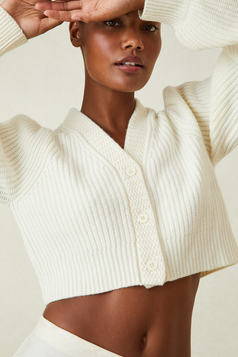  cashmere-wool blend cropped sweater, has a v-neck that descends to three buttons at center front. Pleated blouson sleeves extend to ribbed cuffs at opening.