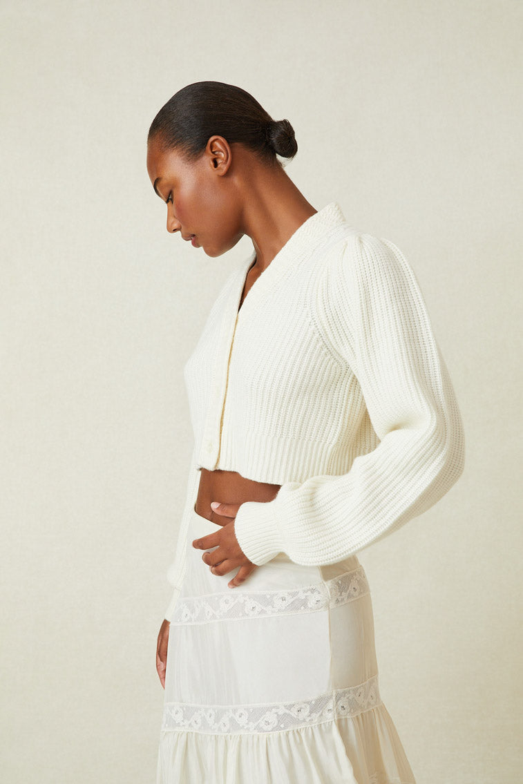 cashmere-wool blend cropped sweater, has a v-neck that descends to three buttons at center front. Pleated blouson sleeves extend to ribbed cuffs at opening.