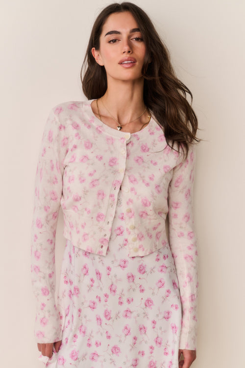 Woman wearing a pink floral cardigan and matching dress against a beige background