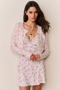 Woman wearing a pink floral cardigan and matching dress against a beige background