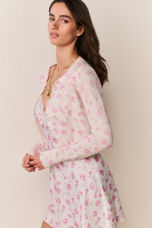 Woman wearing a pink floral cardigan and matching dress against a beige background