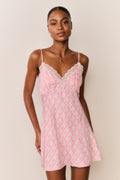 Woman wearing a pink patterned slip dress against a plain background