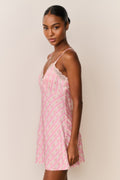Woman wearing a pink patterned slip dress against a plain background