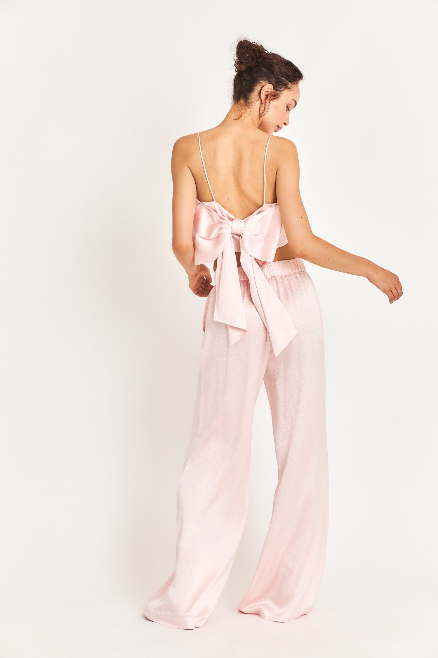 Mid waisted baby pink pants with a wide cut leg that flares out to the bottom