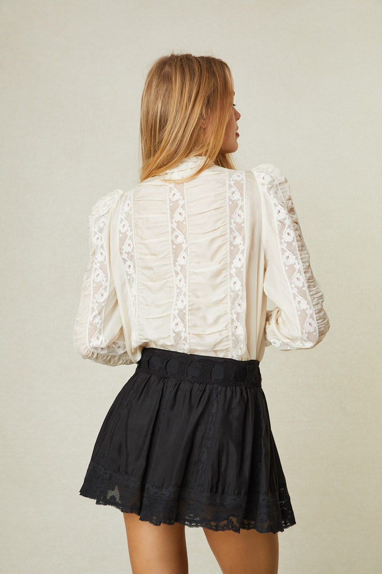 Back image of model wearing black mini skirt with lace detail at hem.