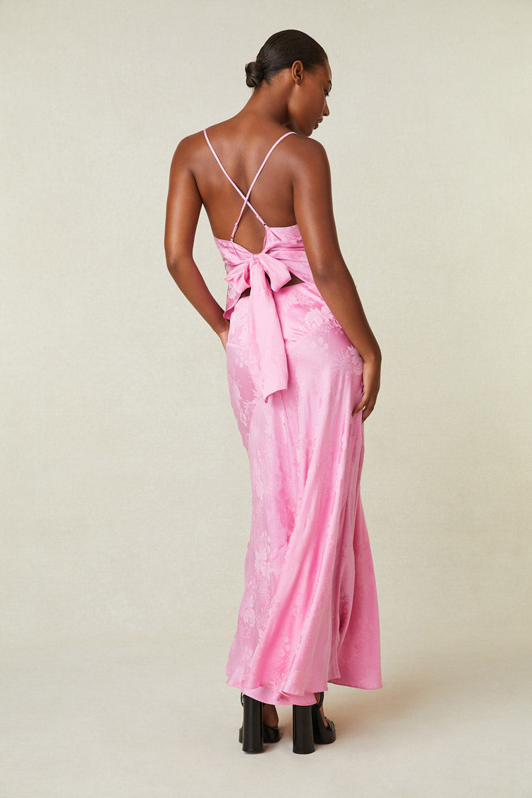 Back image of model wearing pink silk maxi skirt with floral print.