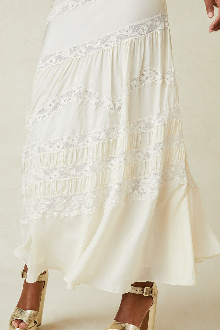 Close up image detailing lace detail on white silk maxi skirt with lace panels