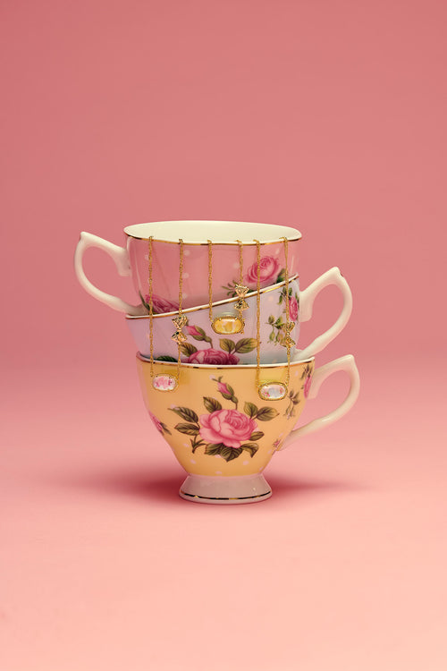 Stack of floral teacups on a pink background