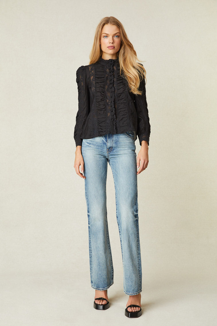 Model wearing black long sleeve blouse with button up front, lace detail, and puff shoulders.