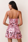 Woman wearing a pink sequin dress against a plain background
