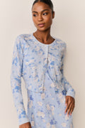 Woman wearing a light blue floral cardigan over a matching dress against a beige background