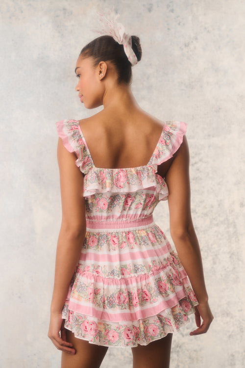 Woman wearing a floral dress with ruffled sleeves against a textured white background