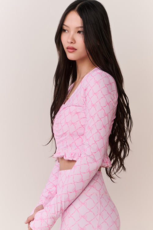 Woman wearing a pink bow patterned workout jacket and matching leggings against a plain background