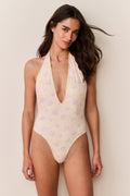 Woman wearing a floral one-piece swimsuit with a neutral background