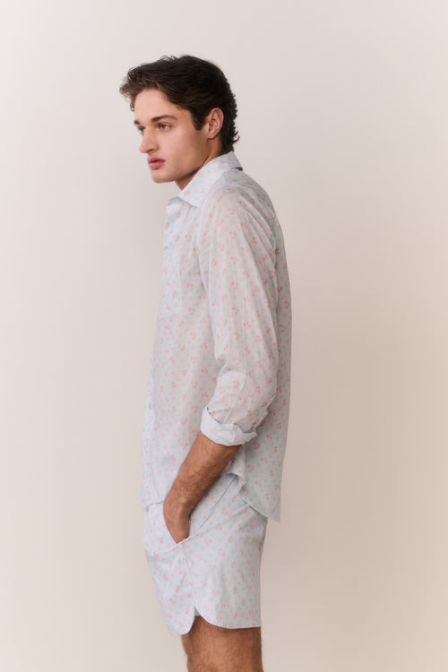 Man wearing a light-colored shirt and shorts against a plain background