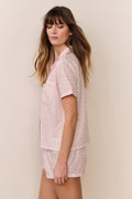 Woman wearing a pink floral pajama set against a beige background