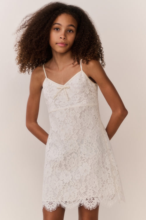 Girl wearing a white lace dress against a plain background