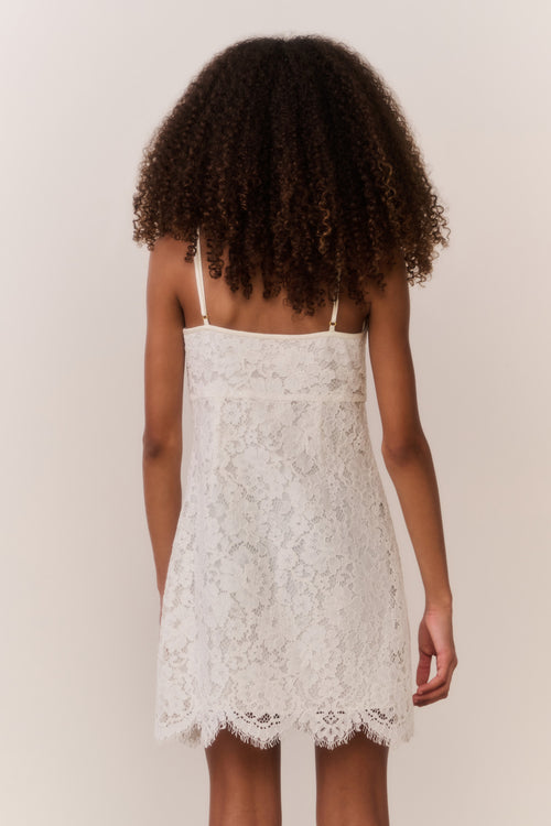 Girl wearing a white lace dress against a plain background