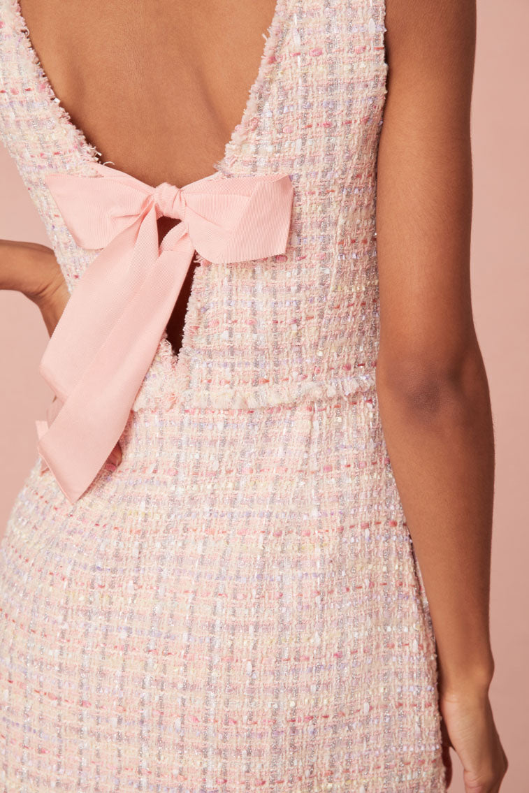 Pink tweed mini dress featuring a scoop neckline, a mod fit that hugs the body then slightly flows out as it descends to a slightly A-line skirt. A deep open back is highlighted by a bow detail.