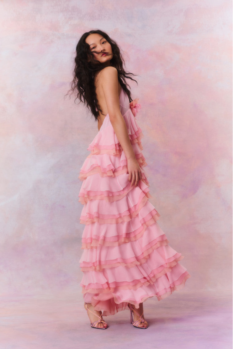 Occasion maxi dress featuring a medley of colors– pinks, corals and creams. Beings with a halter neckline and braided straps before descending to a sweeping, multi-tiered ruffle skirt.