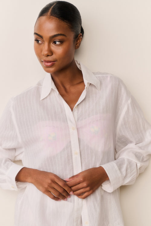 Woman wearing a white button-up shirt against a plain background