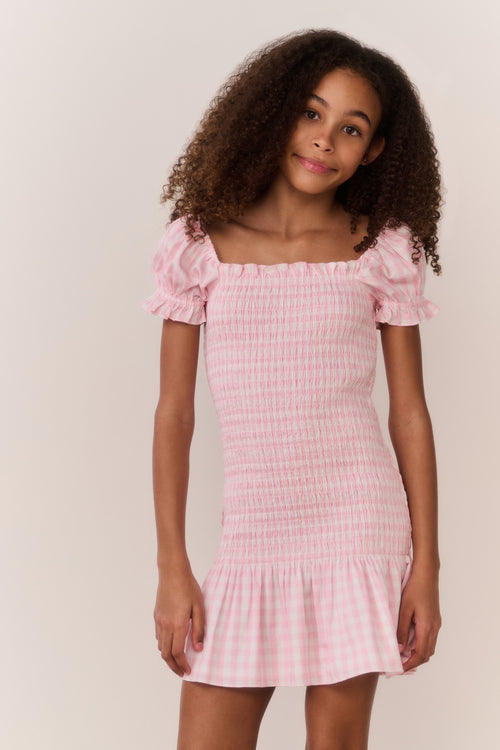 Girl wearing a pink checkered dress with a plain background