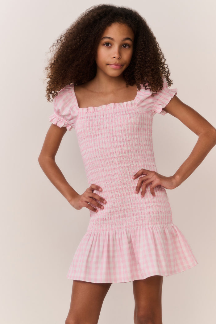 Girl wearing a pink checkered dress with a plain background