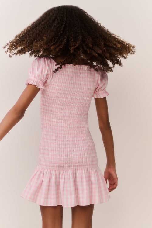 Girl wearing a pink checkered dress with a plain background