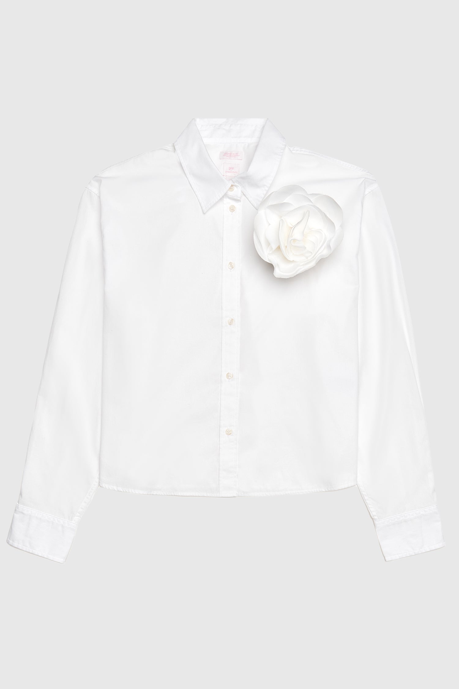 Image of white collared crop shirt with rosette detail on shoulder