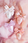 Mini pink perfume bottles with large white bows arranged in tulle