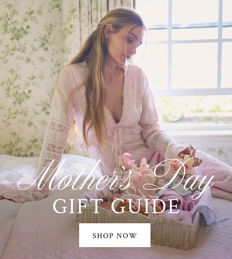 Model sitting on a bed wearing the Weil Dress. Shop our Mother's Day Gift Guide.