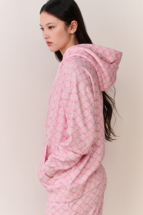 Person wearing a pink bow print jacket and matching sweatpants against a plain background