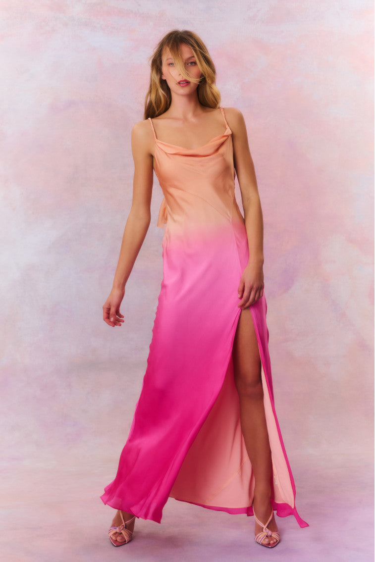 Maxi dress featuring a gorgeous ombré coloring that flows from a bright coral at the top to a fuchsia at the bottom. With a bias cut, this dress begins with twisted chiffon straps and a cowl neck before descending into the figure-hugging bodice that releases into a long skirt with a high slit.