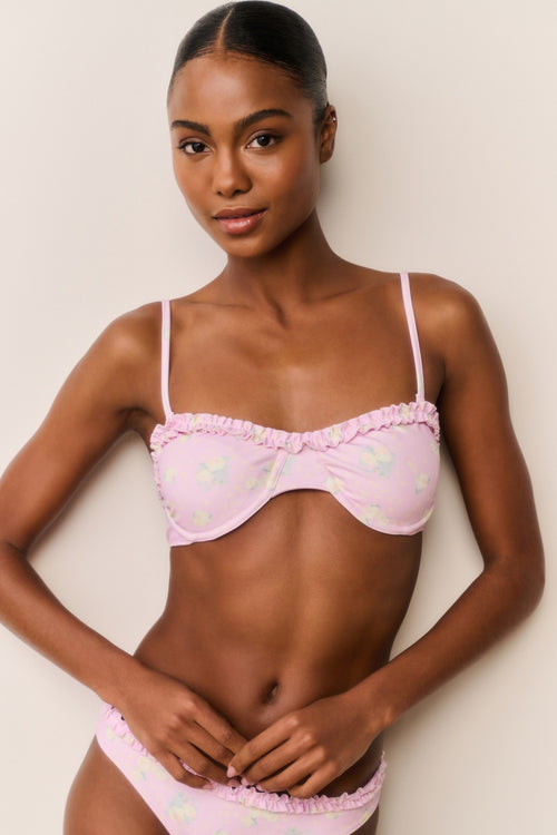 Woman wearing a pink floral bikini with a white background