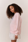 Girl wearing a pink american flag sweatshirt and white lace skirt on a plain background