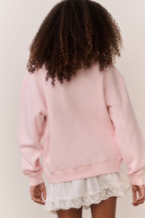 Girl wearing a pink american flag sweatshirt and white lace skirt on a plain background
