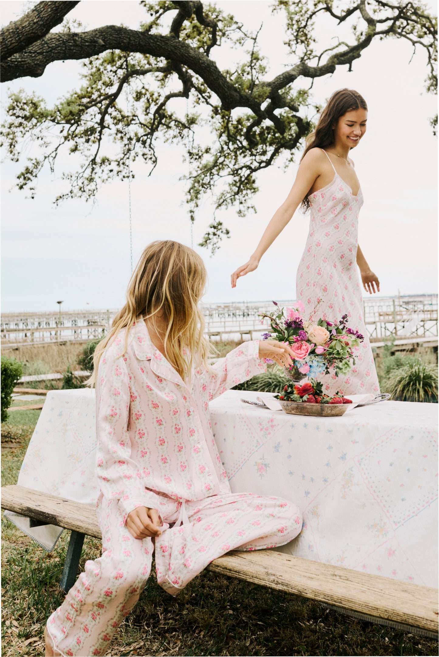 Women sitting in grass field wearing LoveShackFancy Slip Dresses