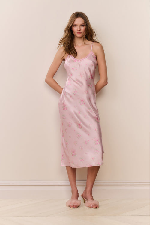 Woman wearing a pink floral slip dress against a plain background