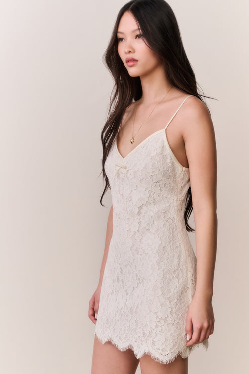 Woman wearing a white lace dress against a plain background