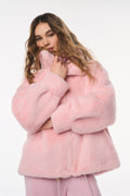 Person wearing a pink fluffy coat on a white background
