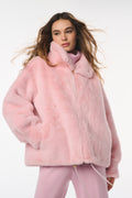 Woman wearing a pink fur coat and pants on a white background