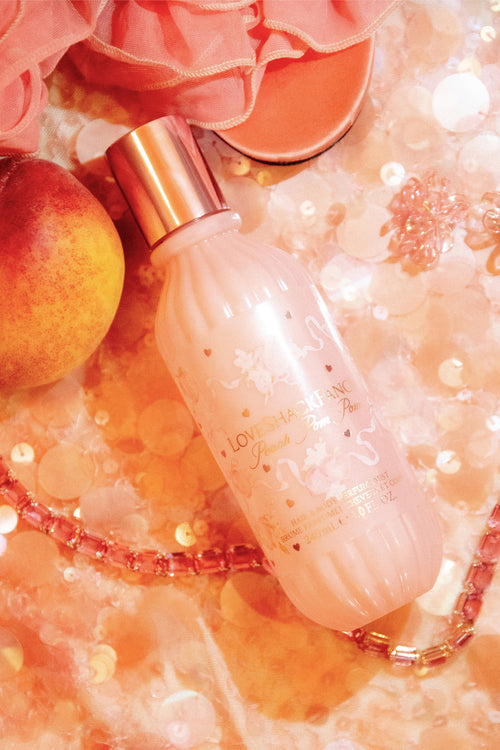 Pink perfume bottle with peach and decorative elements on a soft focus background