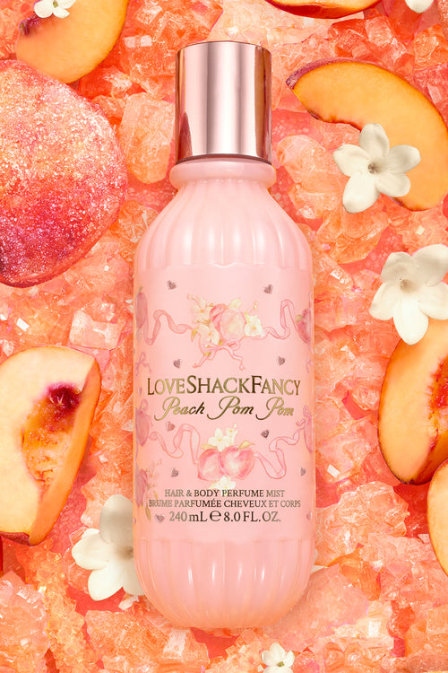 LoveShackFancy peach pom pom perfume bottle on a peach and flower patterned background